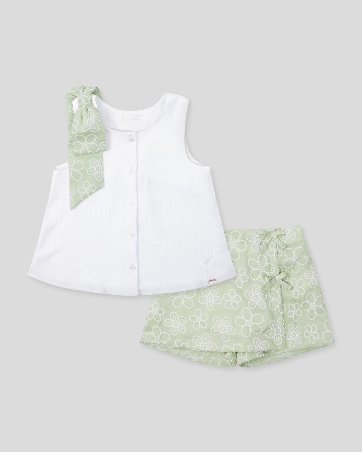 Conjunto blusa blanca con botones, moño y falda short verde estampado para niña