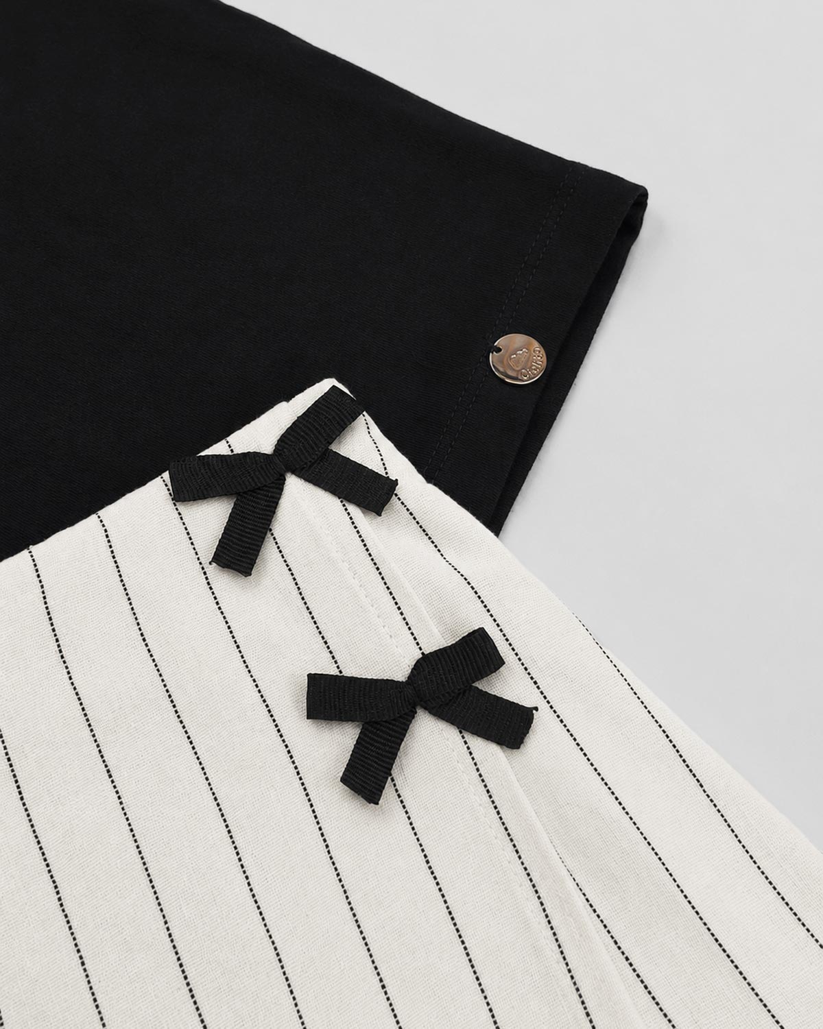 Conjunto blusa negra con moño y falda short en lino con rayas y moñitos para niña
