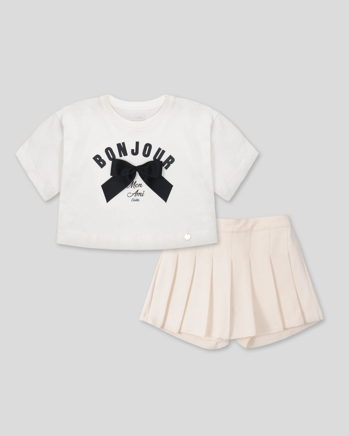Conjunto blusa blanca con estampado y moño y falda short crema para niña