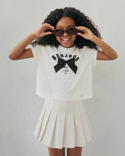 Conjunto blusa blanca con estampado y moño y falda short crema para niña