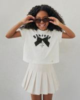 Conjunto blusa blanca con estampado y moño y falda short crema para niña
