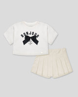 Conjunto blusa blanca con estampado y moño y falda short crema para niña
