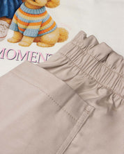 Conjunto blusa blanca estampada con moñitos y short beige para niña