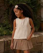 Conjunto blusa en tela hoja rota crema con moñitos y falda short café para niña