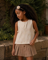 Conjunto blusa en tela hoja rota crema con moñitos y falda short café para niña
