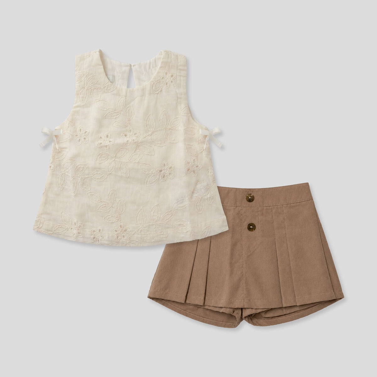 Conjunto blusa en tela hoja rota crema con moñitos y falda short café para niña