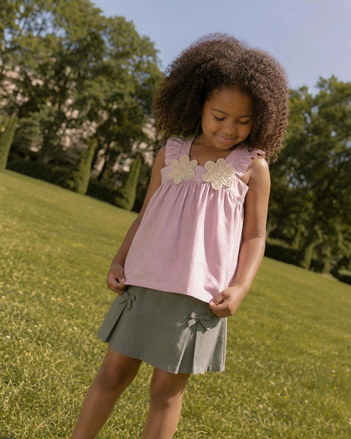 Conjunto blusa rosa de tiras con boleros, apliques de flor y falda short verde con moñitos para niña