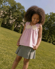 Conjunto blusa rosa de tiras con boleros, apliques de flor y falda short verde con moñitos para niña