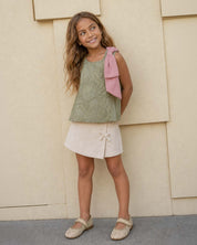 Conjunto blusa verde con flores bordadas, moño rosa y falda short crema para niña
