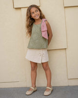 Conjunto blusa verde con flores bordadas, moño rosa y falda short crema para niña
