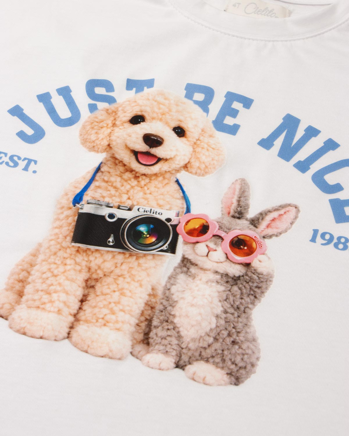 Conjunto camiseta blanca estampada Just Be Nice y falda short azul con moño para niña