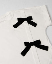 Conjunto camiseta blanca con moños y falda short beige con detalle de lentejuelas para niña
