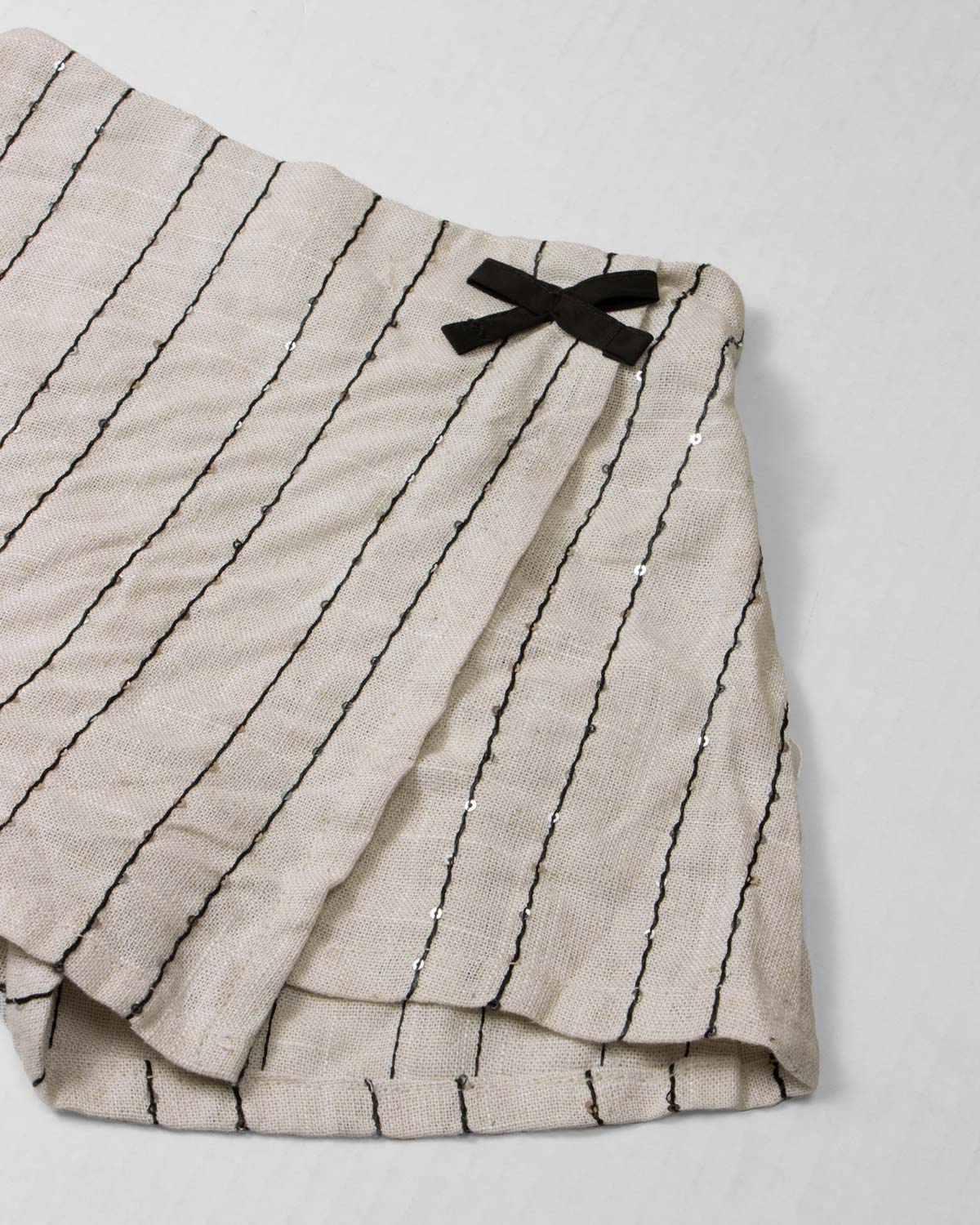 Conjunto camiseta blanca con moños y falda short beige con detalle de lentejuelas para niña