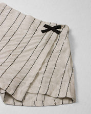 Conjunto camiseta blanca con moños y falda short beige con detalle de lentejuelas para niña