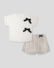Conjunto camiseta blanca con moños y falda short beige con detalle de lentejuelas para niña