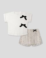Conjunto camiseta blanca con moños y falda short beige con detalle de lentejuelas para niña