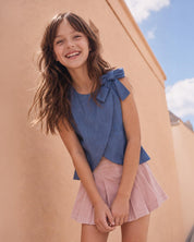Conjunto blusa chambray con moño y falda short rosa con pliegues para niña