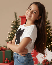 Camiseta con aplique moño en negro y estampado en cuello para niña