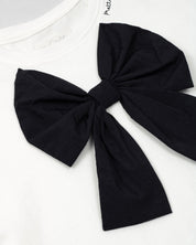 Camiseta con aplique moño en negro y estampado en cuello para niña