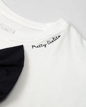 Camiseta con aplique moño en negro y estampado en cuello para niña