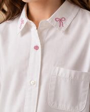Camisa blanca con pequeño bordado de moños y bolsillo para niña