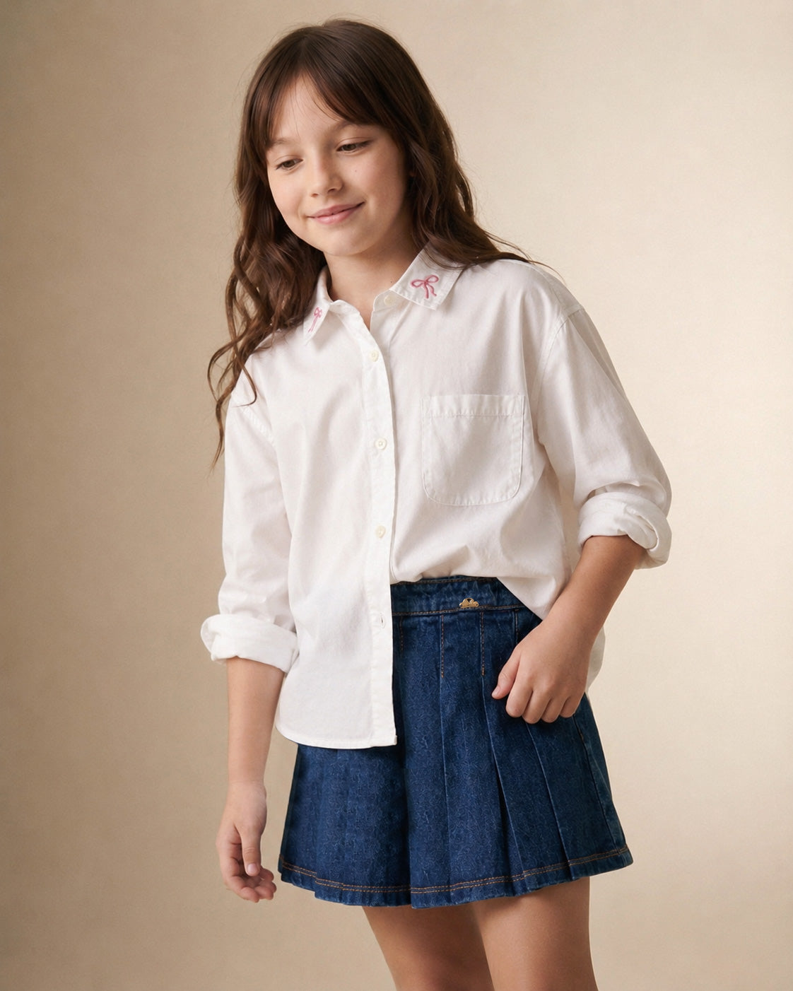 Camisa blanca con pequeño bordado de moños y bolsillo para niña