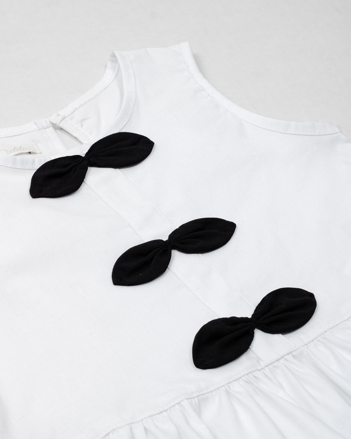 Blusa blanca con moños negros para niña