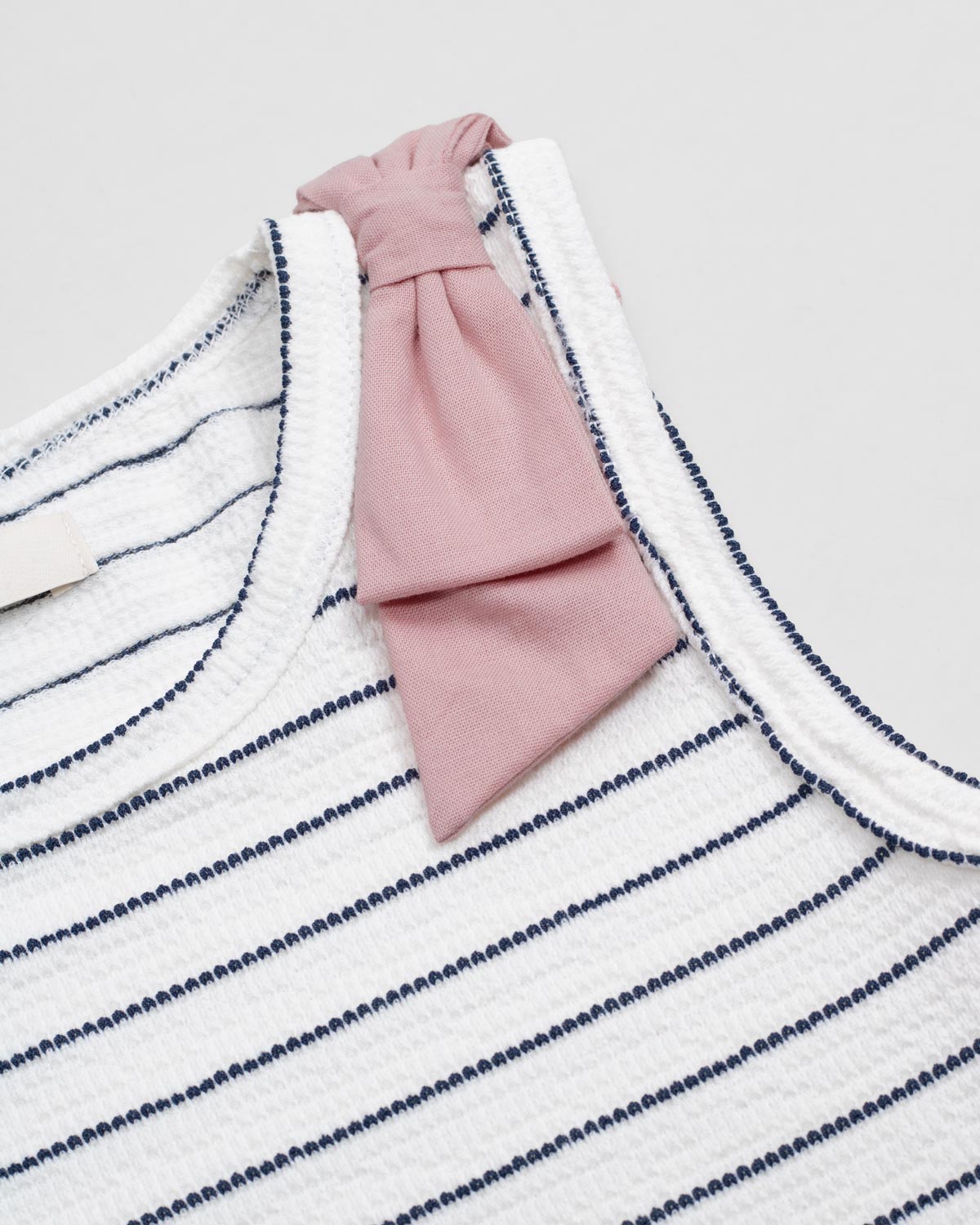 Blusa manga sisa blanca con líneas y moño rosa para niña