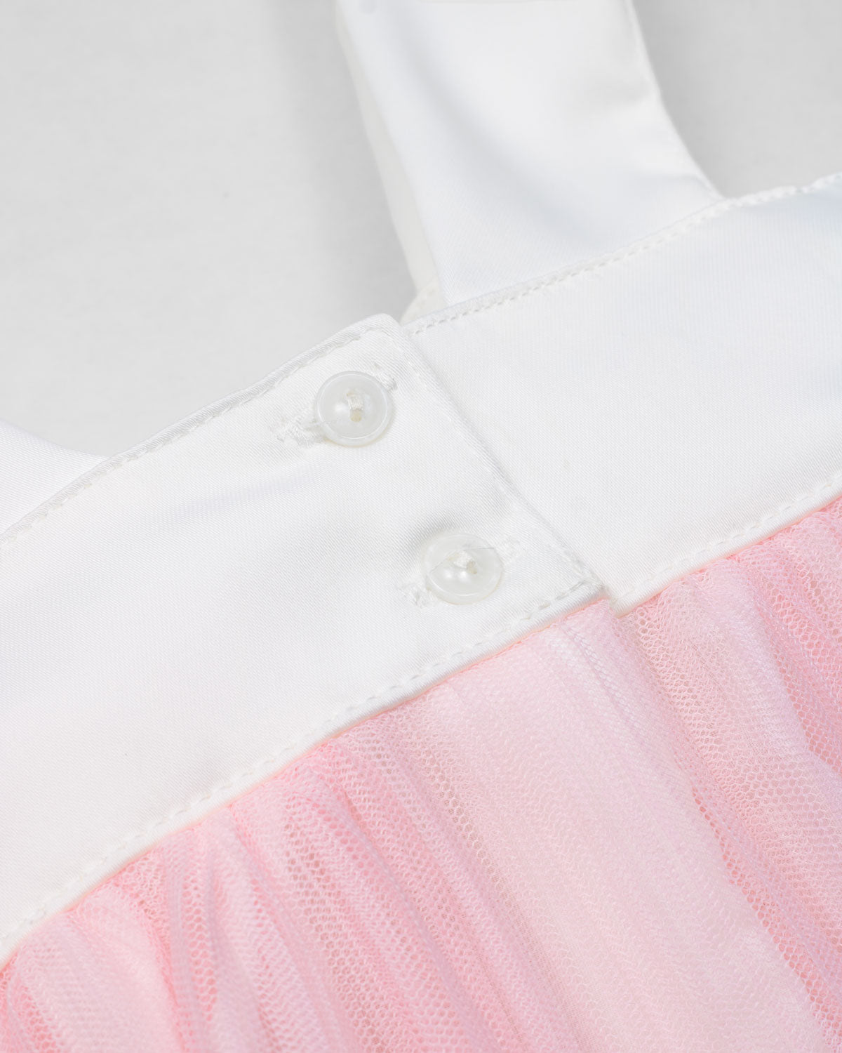 Vestido en satín blanco con moño y tull plisado rosa para niña