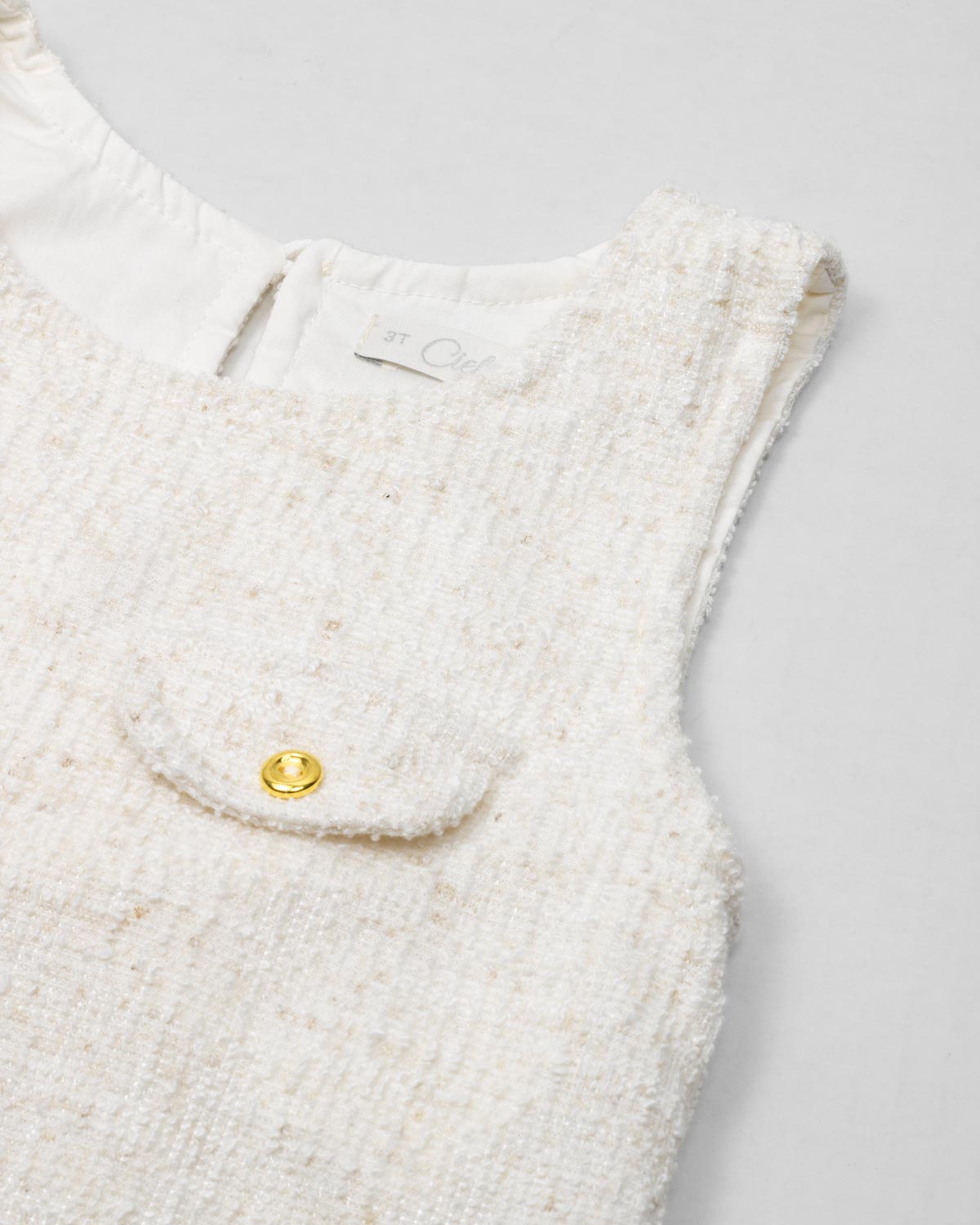 Vestido blanco terminado en bolero con tejido texturizado y bolsito pequeño para niña