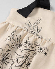 Vestido crema con diseño de flores tejido y tiras con moño para niña