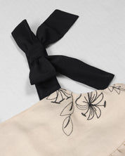Vestido crema con diseño de flores tejido y tiras con moño para niña