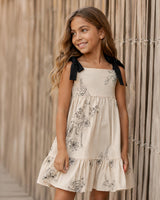 Vestido crema con diseño de flores tejido y tiras con moño para niña