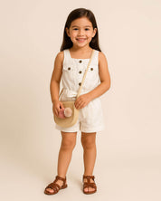 Total look de enterizo blanco, sandalias y bolsos para niña.