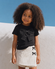 Conjunto blusa negra con moño y falda short en lino con rayas y moñitos para niña
