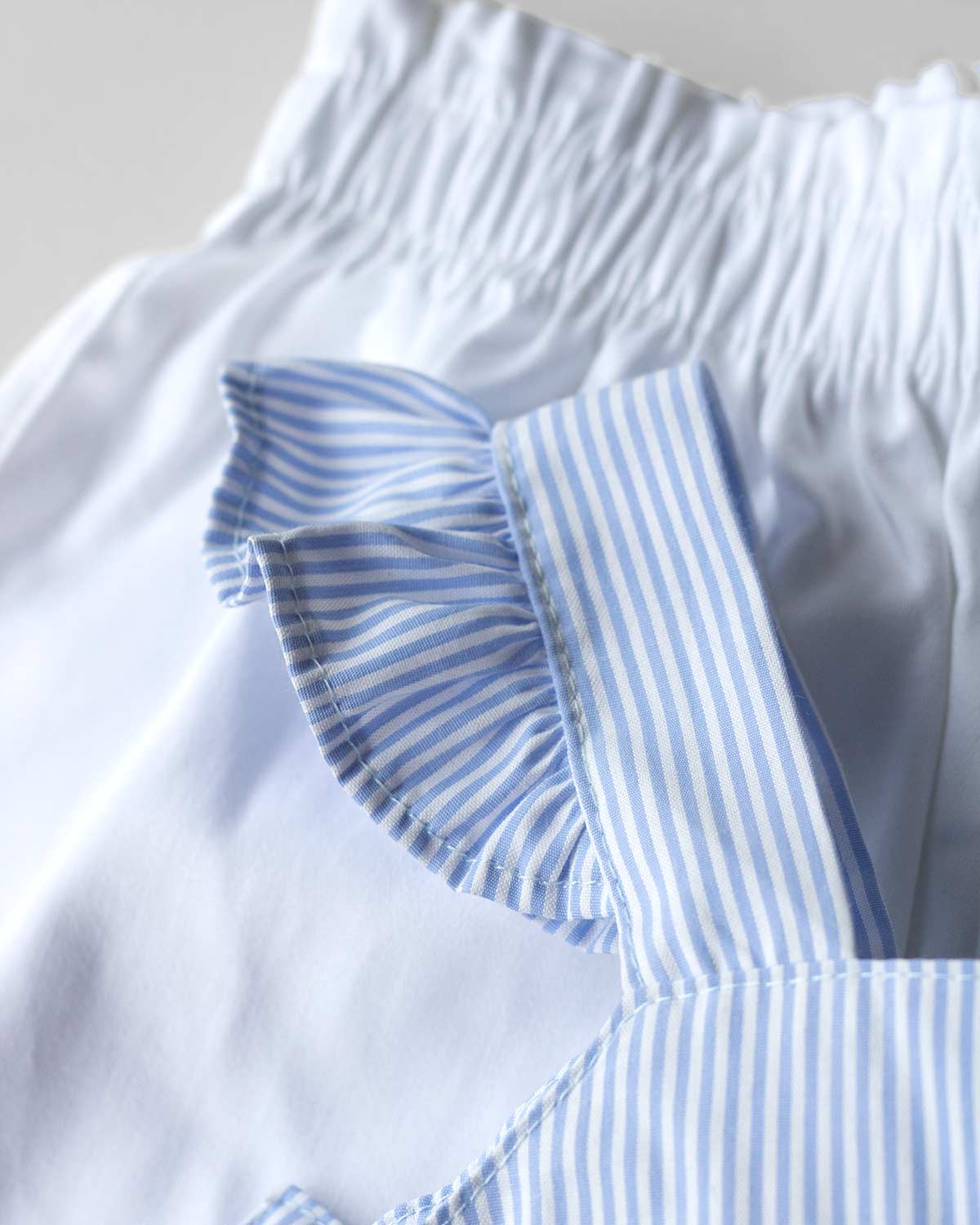 Conjunto blusa azul de líneas con moño en espalda y short blanco para niña